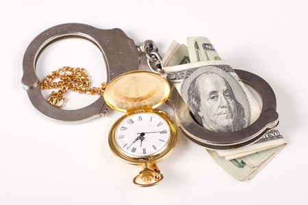 concept of doing jail time for money, handcuffs and time and money over a white backgroundの写真素材