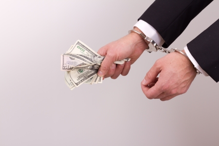 arrested businessman holding hundred dollar bills isolated on a white backgroundの写真素材