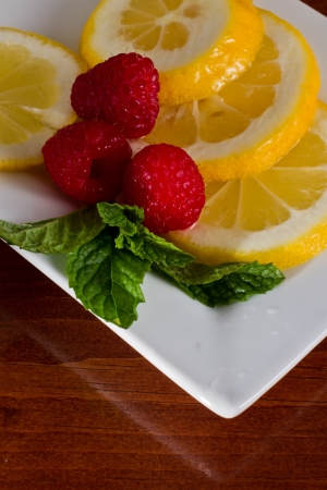 closeup of a white plate with fresh organic lemon mint and raspberriesの写真素材