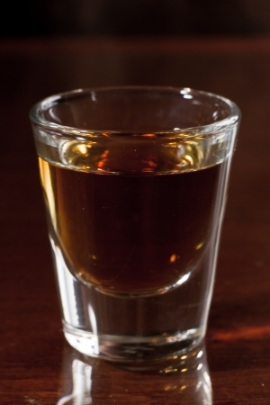 shot glass on a dark bar top with splash of light reflectingの写真素材