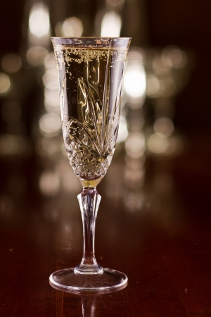single champagne flute on a bar top with a busy out of focus backgroundの写真素材