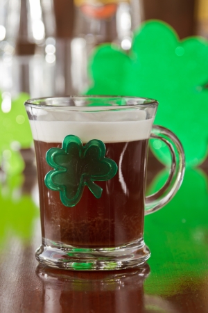 irish coffee served on a bar top with green shamrocks and reflective glassware on the backgroundの写真素材