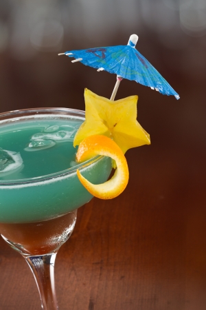 blue hawaiian cocktail served on a busy bar top garnished with a carambola slice and an umbrellaの写真素材