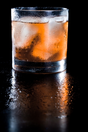 closeup of a manhattan on the rocks served on a dark bar fading in to blackの写真素材