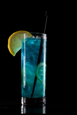 bright blue lemonade served in a tall glass isolated on a black backgroundの写真素材