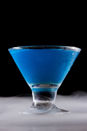small bright blue cocktail on a dark foggy dramatic barの写真素材