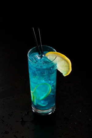 bright blue lemonade served in a tall glass isolated on a black backgroundの写真素材