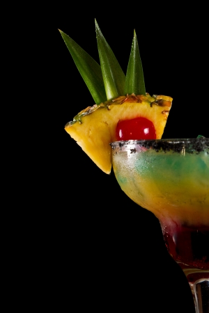pineapple slice with a red cherry on the rim of a glass with a tropical drinkの写真素材