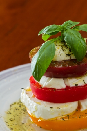 stack of heirloom tomatoes with fresh mozzarella dressed with extra virgin olive oil and fresh green basil spiced with herbs de province from franceの写真素材