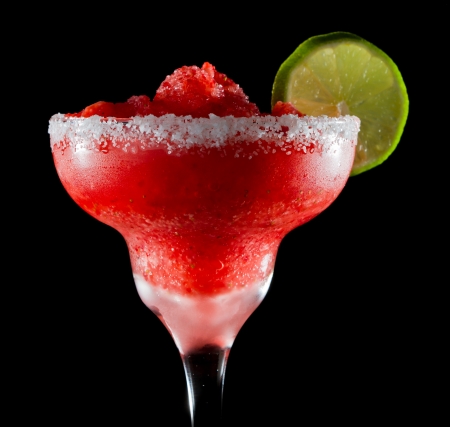 frozen strawberry margarita isolated on a black background garnished with a salt rim and a lime wheelの写真素材