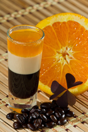 b 52 shots layered and served with an orange and coffee beans on a wooden place mat