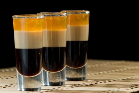 b 52 shots layered and served with coffee beans on a wooden place matの写真素材