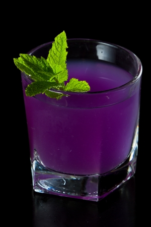 closeup of a purple cocktail isolated on a black background served on the rocksの写真素材