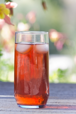 ice tea served outside with a natural green and flower garden in the backgroundの写真素材