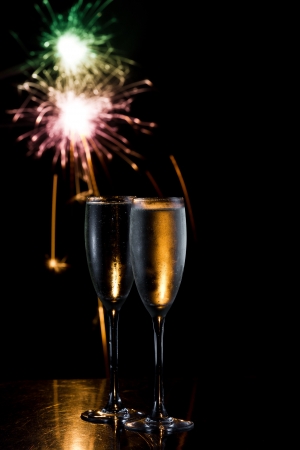 dark scene with two glasses of champagne and fireworks in the backgroundの写真素材