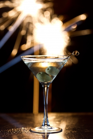 dark scene with a martini glass at night with fireworks in the backgroundの写真素材