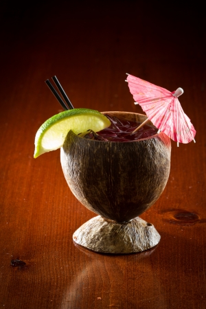refreshing summer drink served in a coconut shell garnished with a lime and a parasolの写真素材