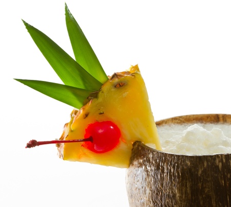 closeup of a tropical coconut drink garnished with a pineapple slice with leaves and a cherryの写真素材