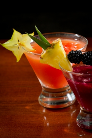 cocktails served in  stemless martini glasses garnished with a pineapple slice, blackberries and star fruitの写真素材