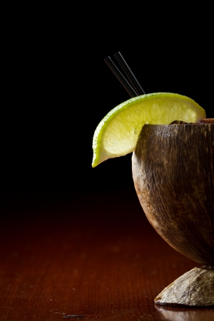 refreshing summer drink served in a coconut shell garnished with a lime and a parasolの写真素材