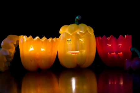 scary faces carved on bell peppers on a dark background for halloweenの写真素材