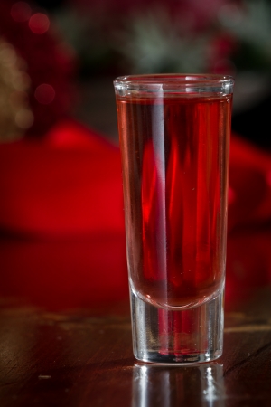 red holiday shot served in a clear tall glass with an out of focus christmas backgroundの写真素材