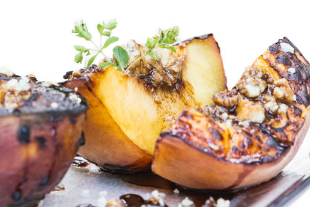 close up of grilled peaches with blue cheese and a balsamic reduction on a white backgroundの写真素材