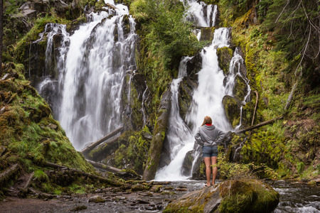 pretty woman relaxing and enjoying serene scene of national creek falls in Oregonの写真素材