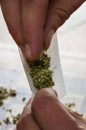 close up of fingers rolling a marijuana joint  with a shallow depth of fieldの写真素材