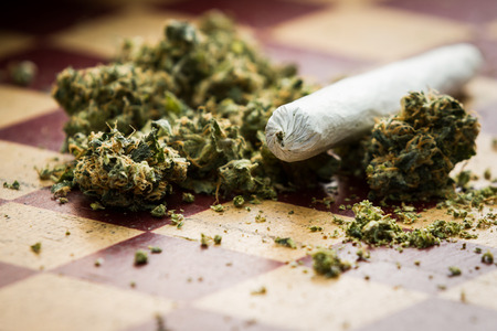 closeup of marijuana joint and buds on a checkerboard table with a shallow depth of fieldの写真素材