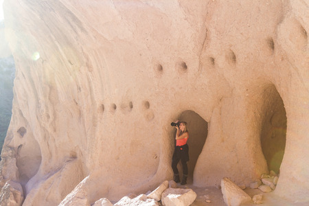 beautiful woman taking a picture from caves in Bandelier national Monument in New Mexicoの写真素材