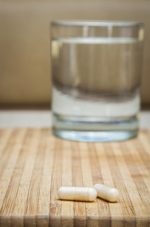 concept image with supplements on a table and a glass of water in the backgroundの写真素材