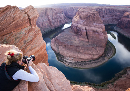 photographer taking a picture of Horse Shoe Bend in Arizona, belly crawling to cld edge of the cliffの写真素材