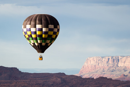 hot air balloon floating over the red navajo sandstone in Arizona with a beautiful landscapeの写真素材