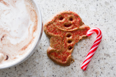 hot chocolate with a gingerbread man with a missing foot using a candy cane