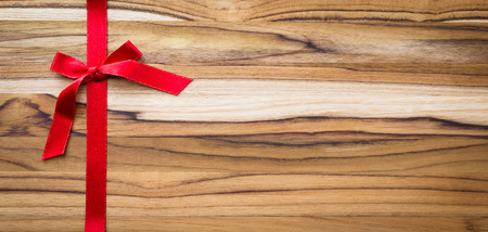 red ribbon and bow on a beautiful and exotic wooden backgroundの写真素材