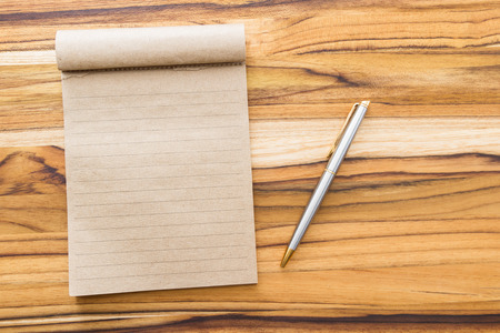 fresh cup of coffee and a blank recycled note pad on a wooden backgroundの写真素材