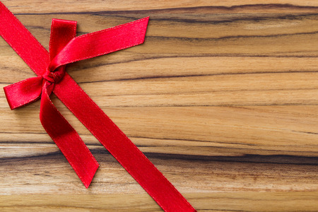 red ribbon and bow on a beautiful and exotic wooden backgroundの写真素材