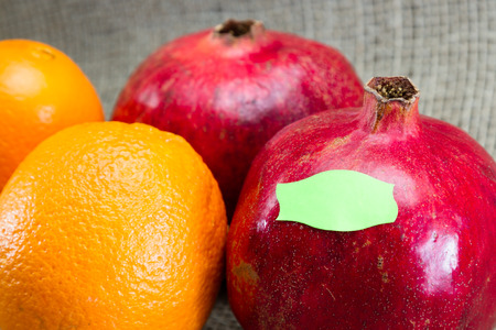 fresh pomegranates and oranges for a concept of labeling gmo vrs organic foodsの写真素材