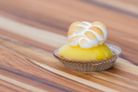 close up of a small lemon meringue on a wooden tableの写真素材