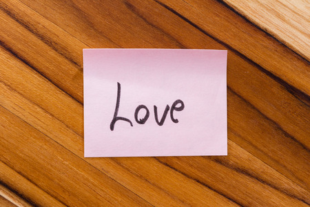 small pink note with the word love on an office desk backgroundの写真素材