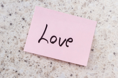 small pink note with the word love on an office desk backgroundの写真素材