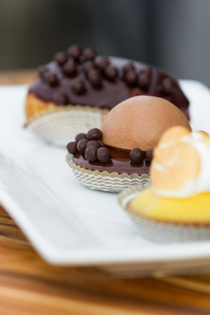 serving of three small desserts on a white plate with a chocolate mousse in focusの写真素材