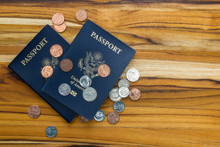 close up of two american passports and coins for a cheap travel conceptの写真素材