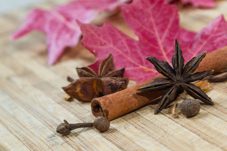 close up of cinnamon and anise stars with autumn leaves on a wooden backgroundの写真素材