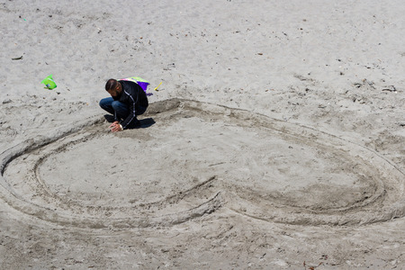 San Luis Obispo, California - May 03 : young man making a hart shape with sand on the beach, May 03 2015 San Luis Obispo, California.のeditorial素材