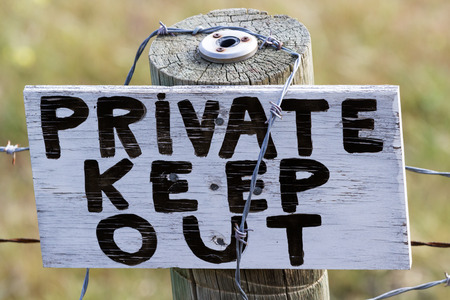 close up of a sign on a fence post with barb wireの写真素材