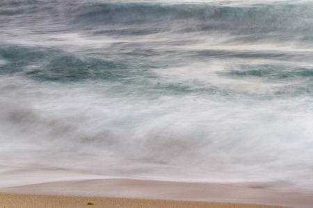 view of a desolate beach shot using a slow shutter speed to show motion in the wavesの写真素材