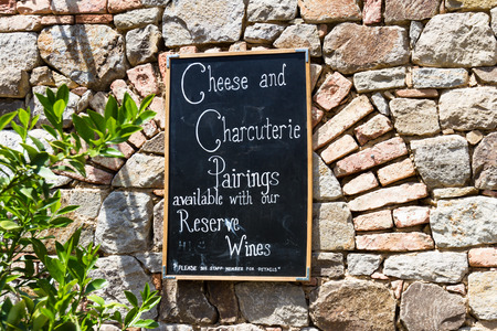 a black board on an old brick wall offering cheese and charcuterie with wine pairingsの写真素材