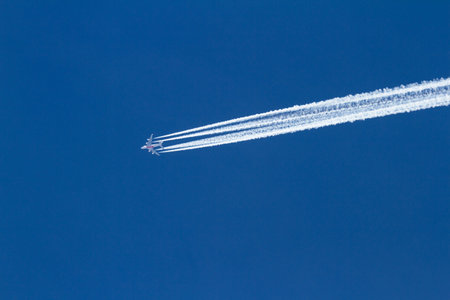 Diamond Lake, Oregon - May 24 : Emirates airplane flying over a beautiful blue sky leaving behind a...